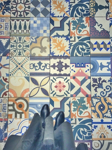 selfeet on a colourful mosaic tile floor. black rain boots and a leather skirt. photo