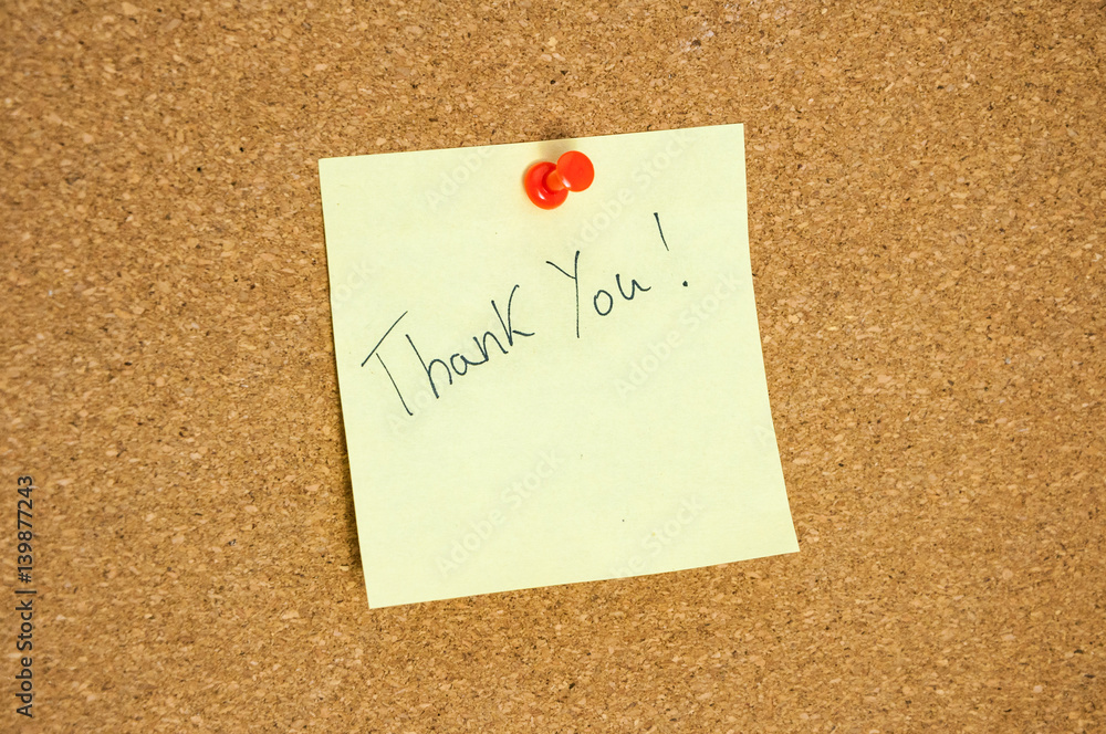 Paper note written with THANK YOU inscription on cork board