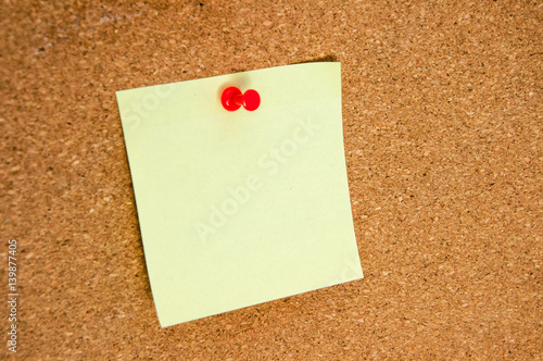 Empty yellow sticker for notes on the cork board close-up.