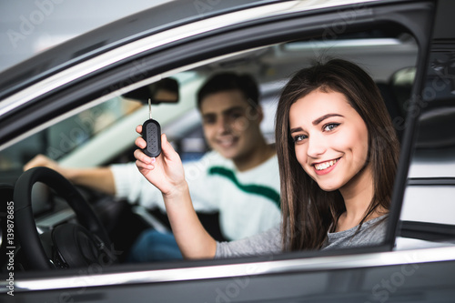 Beautiful young couple sitting at the front seats of their new car while woman showing keys and smiling © F8  \ Suport Ukraine