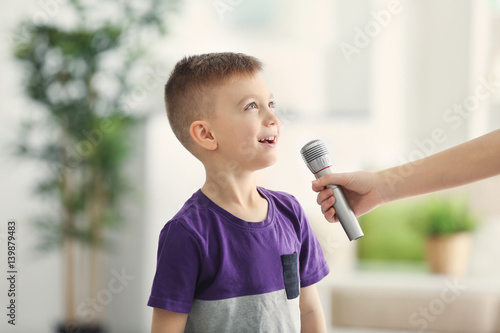 Female hand giving microphone to cute little boy at home