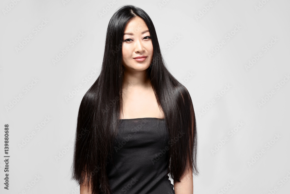 Beautiful Asian woman with long straight hair on light background Beautiful Asian woman with long straight hair on light background