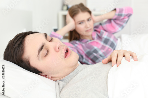 Canvas-taulu Snoring man in bed and blurred irritated woman on background
