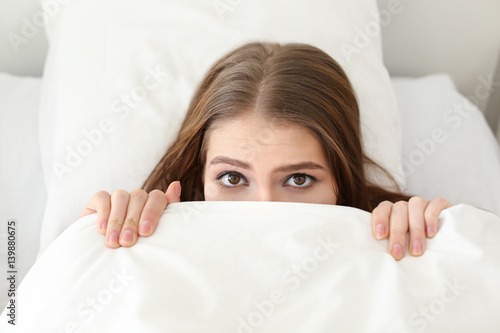 Young woman hiding under bl...
