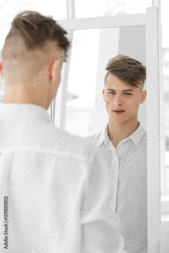 Handsome young man looking at mirror