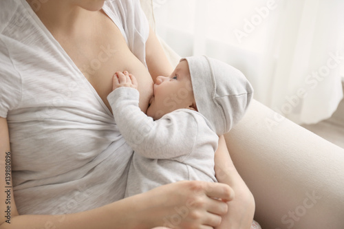 Obraz na plátně Young woman breastfeeding her little baby at home