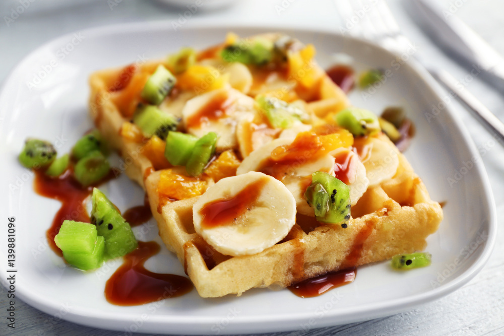 Delicious waffle with fruits and syrup on white plate Delicious waffle with fruits and syrup on white plate