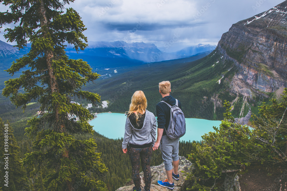 Naklejka premium Couple on the top of the mountains looking at Lake Louise