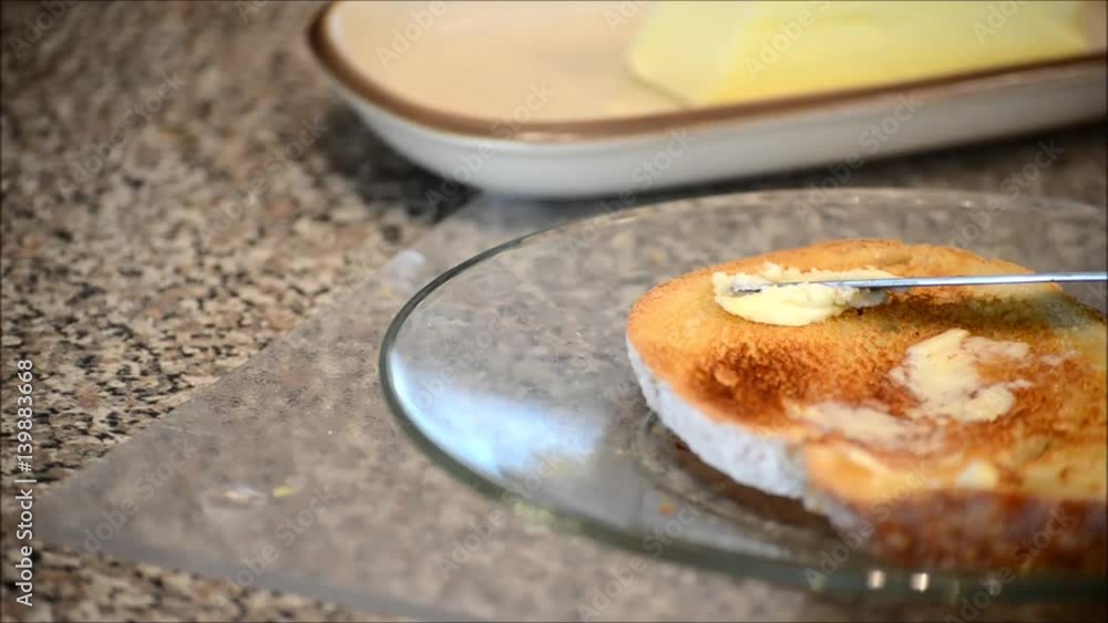 Close up of toasted English muffin while butter is being spread Close up of toasted English muffin while butter is being spread
