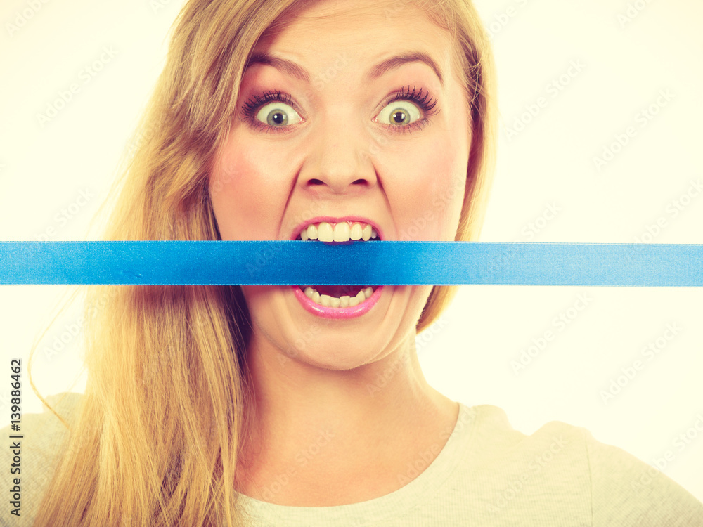 Attractive blonde woman biting tape on mouth.