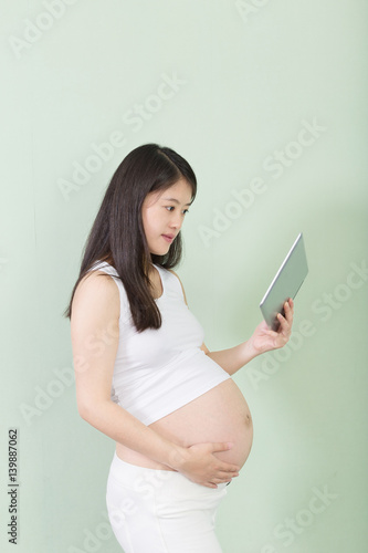 young pretty pregnant woman with tablet