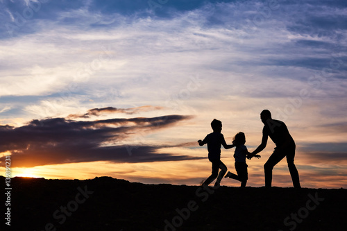 Father and children on the beach at the sunset time. Concept of friendly family.