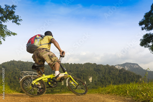 Man asian backpack riding his bike and background of cliff and mountain