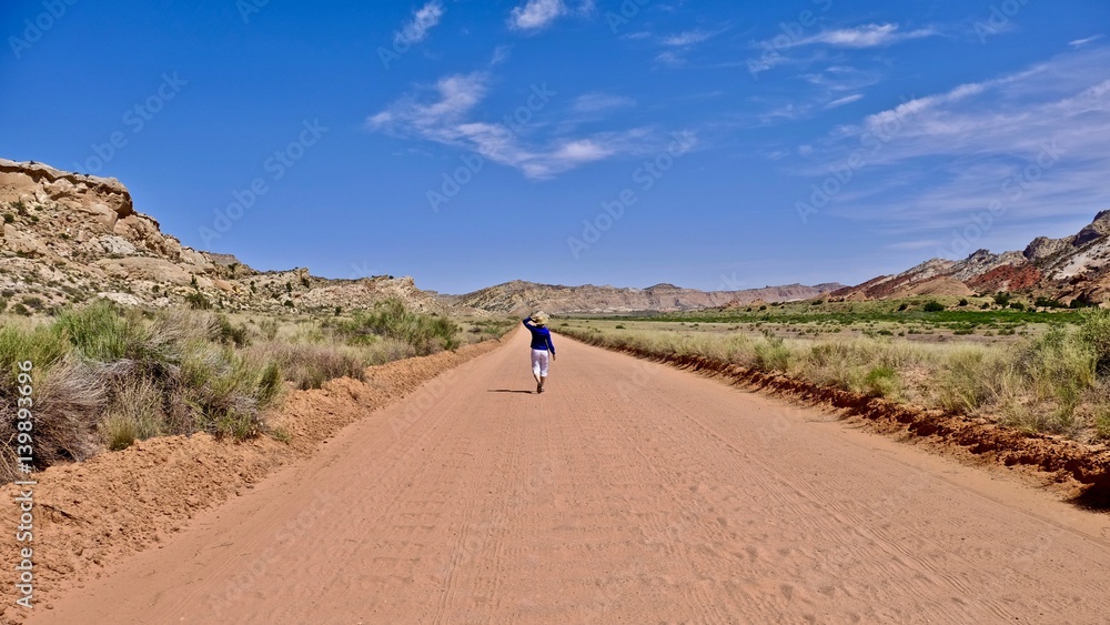 Woman walking on washboard dirt road in deset. Escalante National Monument. Moab. Kanab. Utah. United States.