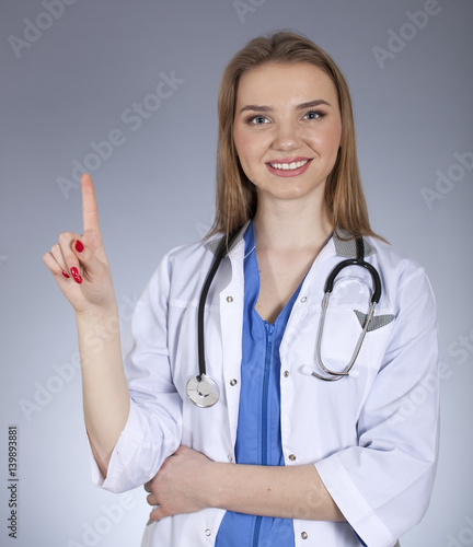 Young  attractive woman doctor holds  index  finger up and smile. 