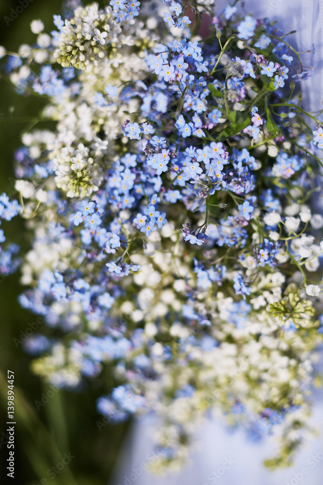 blue bouquet in hands of the girl in a blue dress. Lilies of the valley and forget-me-nots blue bouquet in hands of the girl in a blue dress. Lilies of the valley and forget-me-nots