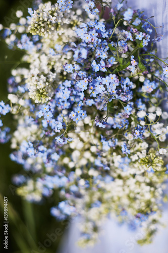 blue bouquet in hands of the girl in a blue dress. Lilies of the valley and forget-me-nots