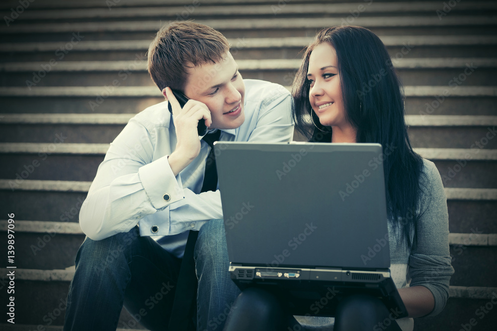 Young business couple with laptop on the steps Young business couple with laptop on the steps