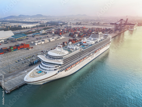 passenger ship cruise is alongside berthed the terminal in port for transit the tourist in port congestion of berth in sunrise in background, in aerial view