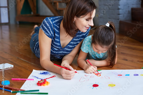 young mother teaches her daughter to draw