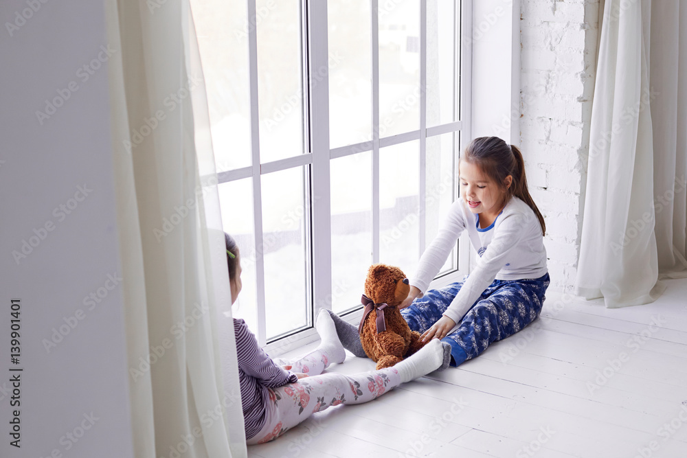 two little girls playing with a teddy bear two little girls playing with a teddy bear