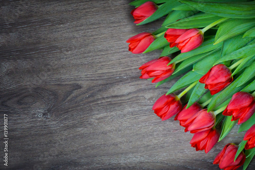 Red tulips on wooden background with space for text