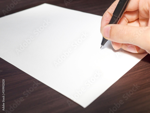 Human Hand Signing on Formal Paper at the Table on Black Background. photo
