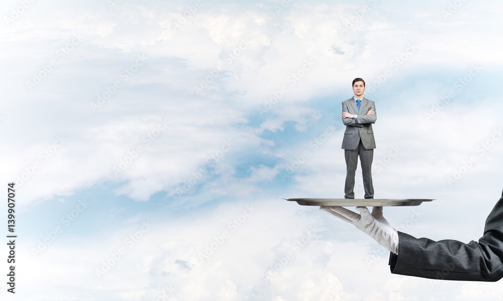 Confident businessman presented on metal tray against blue sky background Confident businessman presented on metal tray against blue sky background