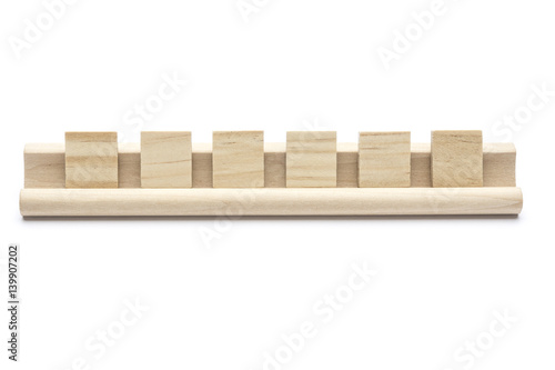 Six blank scrabble tiles on a wooden rack, on white background photo