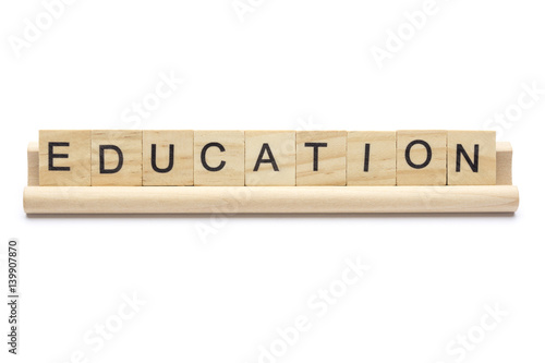 Word ''education'' on scrabble wooden letters on a rack, isolated on white background.