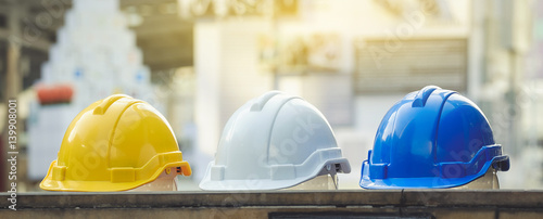 white, yellow and blue hard safety helmet hat for safety project of workman as engineer or worker, on concrete floor on city photo