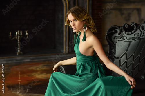 Valokuvatapetti Elegant young woman in green evening dress posing in vintage interior