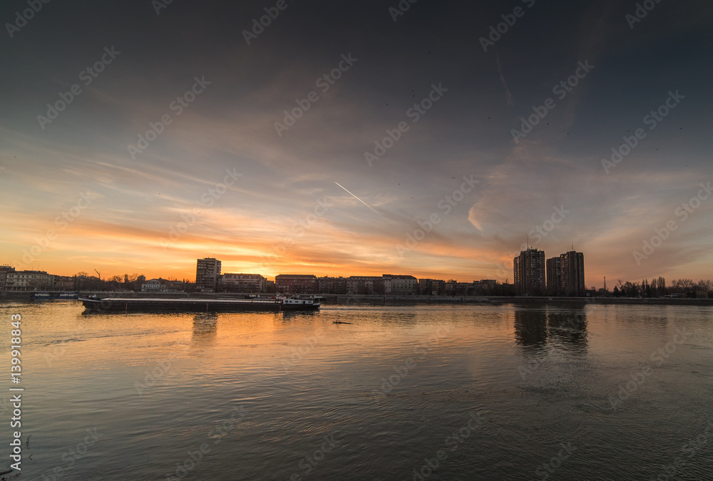 City panorama during warm sunset with buildings and colorful sky over river