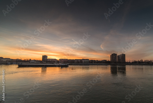 City panorama during warm sunset with buildings and colorful sky over river