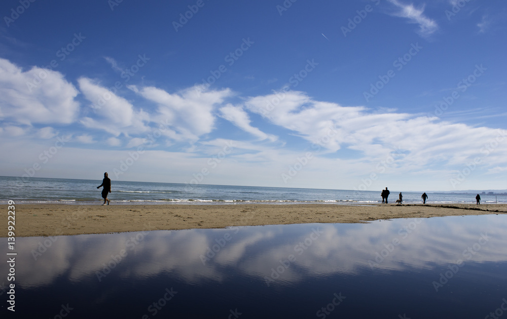 People walking on the beach with clouds