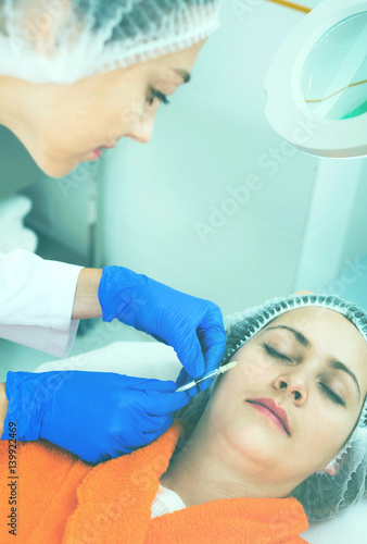 Female doctor doing beauty injection to young woman client