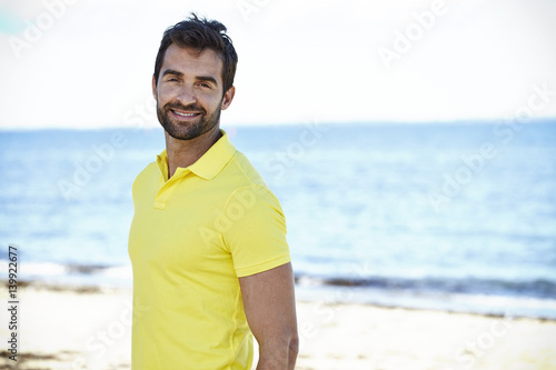 Happy guy in yellow shirt on beach, portrait