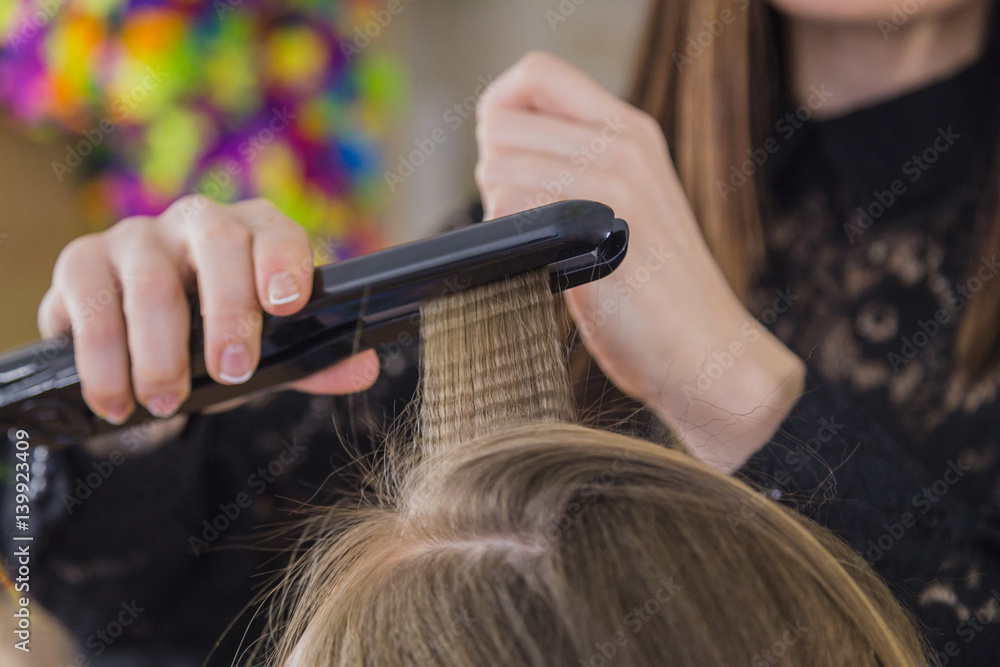 Closeup of hairdresser straightening the hair of a client Closeup of hairdresser straightening the hair of a client