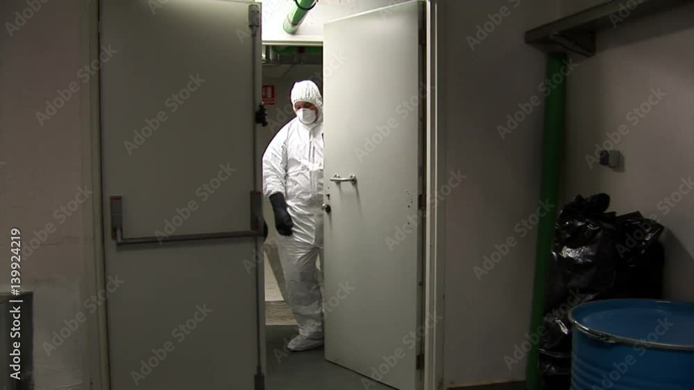 Men in protective suit walk out of storage room and close the doors behind them Men in protective suit walk out of storage room and close the doors behind them