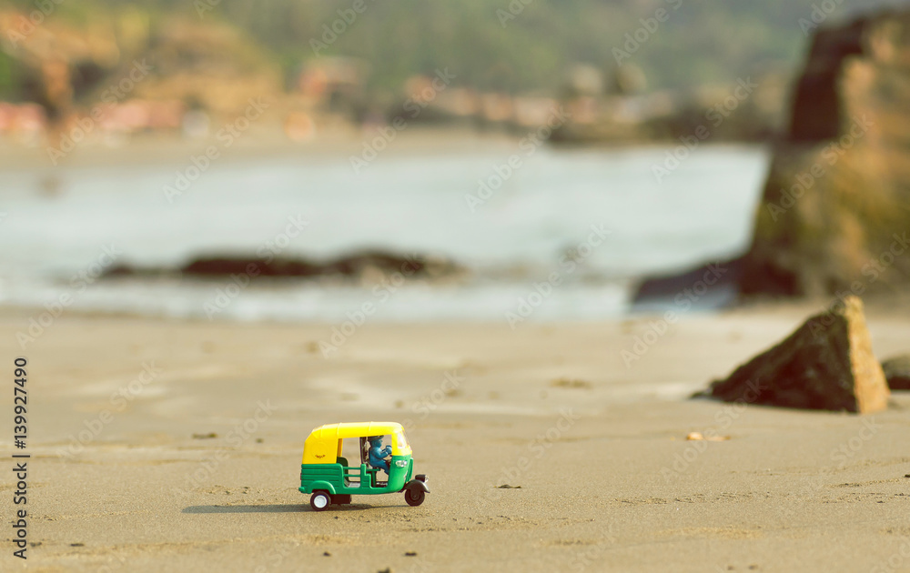 Tiny model of auto rickshaw moves across a sandy Goa beach in India. Tiny model of auto rickshaw moves across a sandy Goa beach in India.