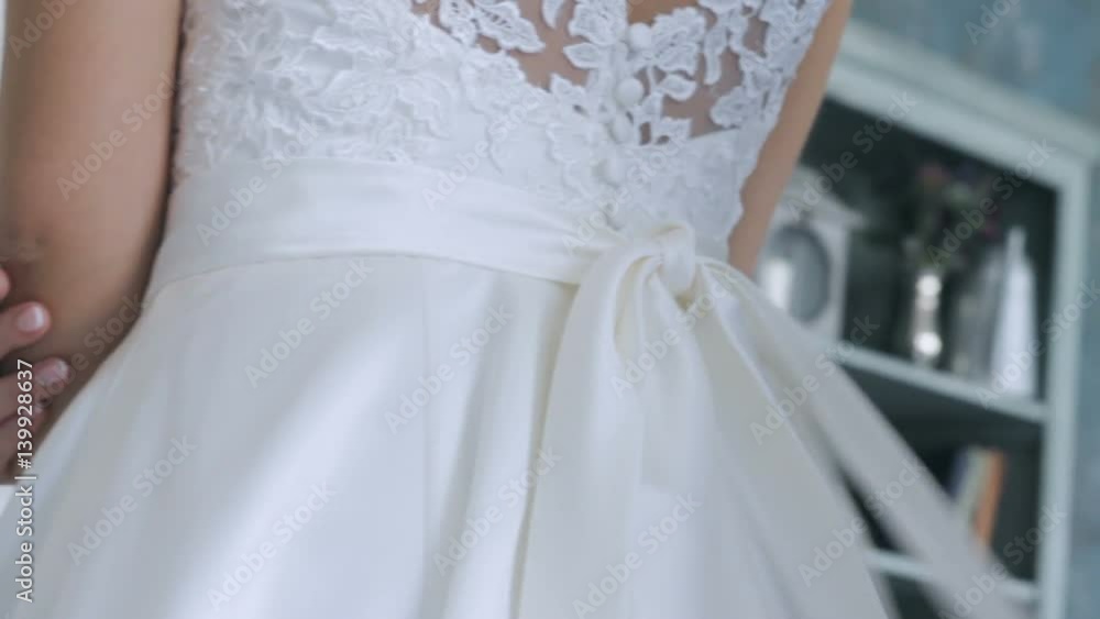 Woman tying bow on the bride's dress back close-up Woman tying bow on the bride's dress back close-up