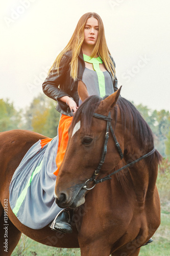 A beautiful girl is walking her horse. Focus on the girl. The warm tone of the image. Soft focus.