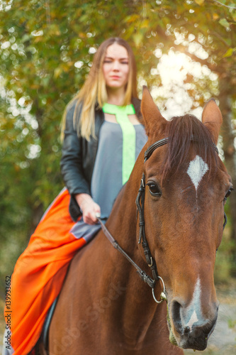 A beautiful girl was walking her horse. Focus on the horse. The warm tone of the image. Soft focus.