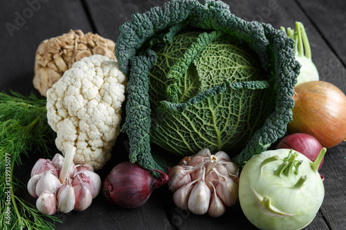 Spring vegetables on a dark background: Savoy cabbage, cauliflower, onion, garlic, kohlrabi, celery root, dill