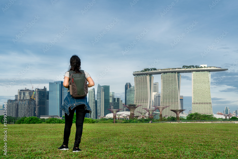 Asian woman traveler in Singapore looking at city view with backpack. Solo woman traveler backpacker in Singapore.