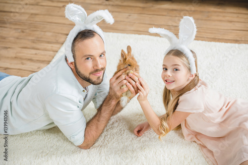 Father and daughter playing with rabbit