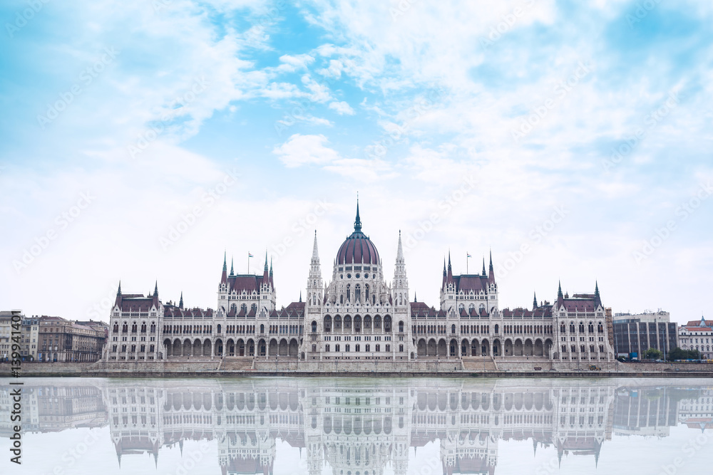 Fototapeta premium Parliament building in Budapest, Hungary on a cloudy day. Building facade with reflection in water