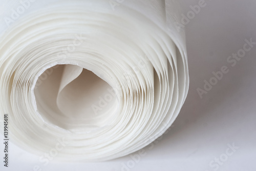 A shallow depth of field closeup photo of a white paper roll on a light background