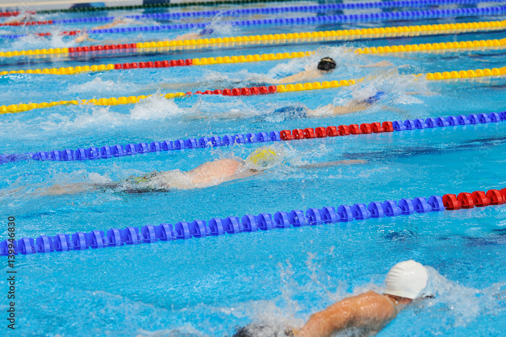 Swimming: A young athletes is swimming in Butterfly Stroke in a blue water swimming pool.