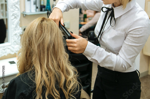 Stylist making evening hairstyle girl with blond hair